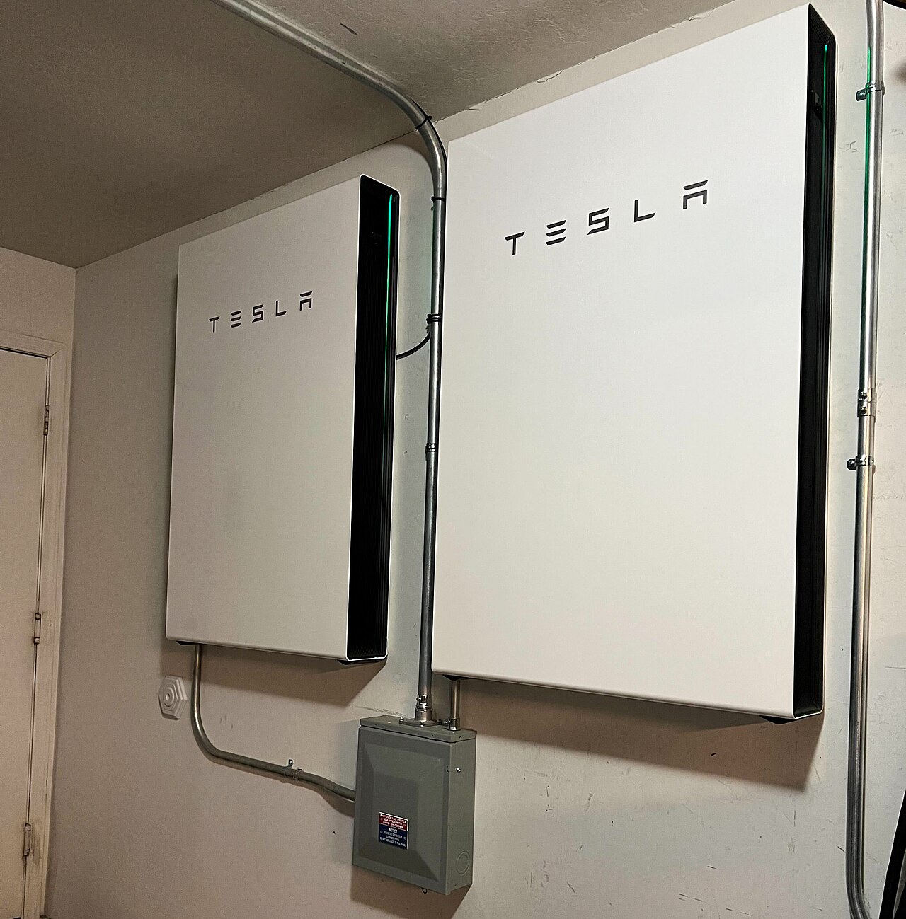 Home batteries installed indoors in a residential property Two wall-mounted home energy storage batteries and a disconnect box installed indoors in a residential property