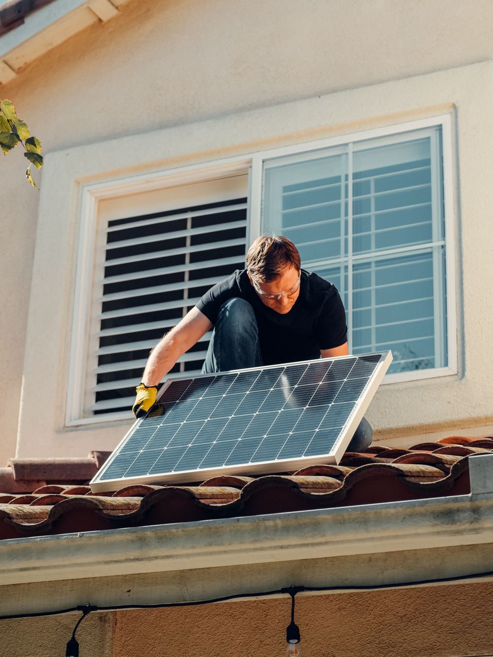Installer fitting a solar panel on a residential roof before adding a home solar battery
