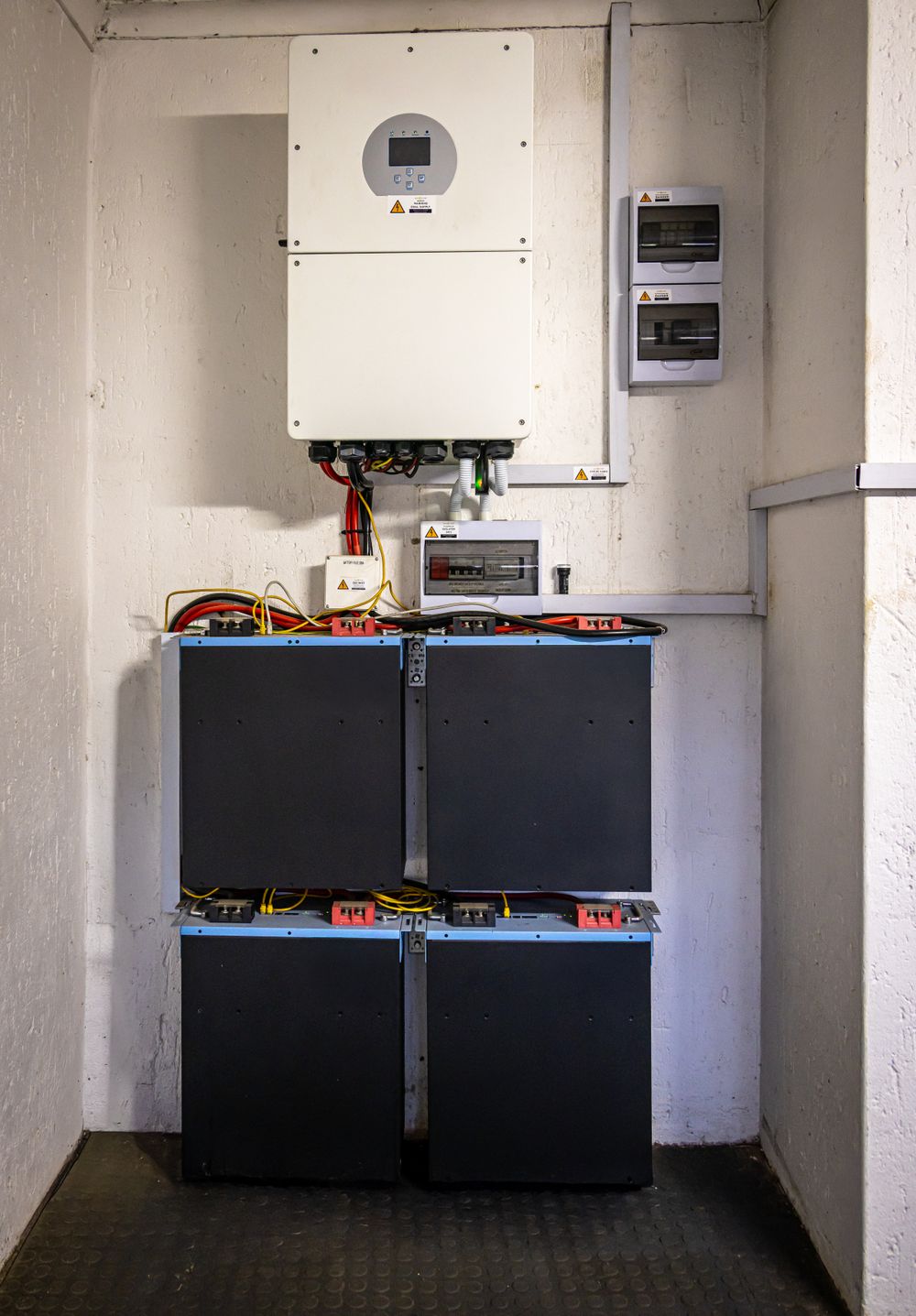 Wall-mounted hybrid inverter above a stacked home solar battery system